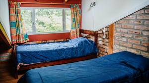 two beds in a room with a window at La Curva in El Bolsón