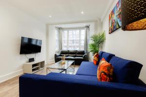a living room with a blue couch and a tv at Central Apartments near Marble Arch in London