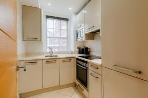 a kitchen with white cabinets and a window at Central Apartments near Marble Arch in London