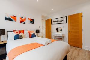 a bedroom with a large white bed with orange accents at Central Apartments near Marble Arch in London