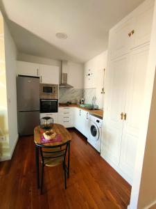 a kitchen with white cabinets and a table in it at Apartamentos Principe in Vigo +29 photos