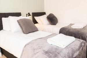 Tres camas en una habitación con sábanas blancas y grises. en Charlotte House Spacious 2br 2bath In Ipswich, en Ipswich