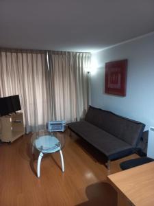 Una sala de estar con un sofá y una mesa de cristal. en Apart Hotel Agustinas Plaza, en Santiago