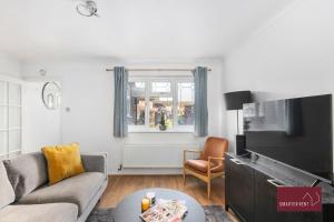 a living room with a couch and a tv at Guildford - Two Bed House in Guildford