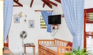 デエエにあるAppartement spacieux avec piscine à Deshaies 200 m² - Jardin privéのベッドと壁掛けテレビのある寝室