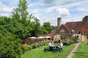 a group of people sitting at picnic tables in a garden at The Merry Harriers Pub in Hambledon
