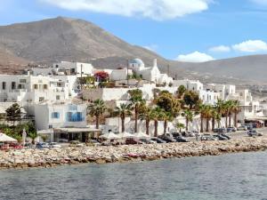 Un grupo de edificios blancos y una playa con palmeras. en Charming House in Paros, 90 m² with Shared Pool, en Parikia