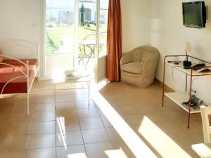 un soggiorno con divano, sedia e TV di Maison charmante à Gallargues-le-Montueux avec piscine partagée a Gallargues-le-Montueux