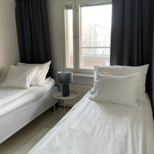 a bedroom with two beds with white pillows and a window at Henniina V Isokatu - Sauna & Free Parking in Oulu