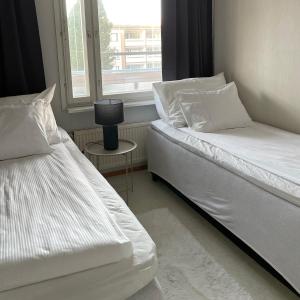 two beds in a small room with a window at Henniina V Isokatu - Sauna & Free Parking in Oulu +8 photos