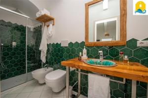 a green tiled bathroom with a toilet and a sink at Casa Angelie in Praiano