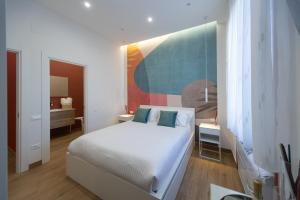 a bedroom with a white bed and a painting on the wall at City Rooms 74 in Salerno +39 photos