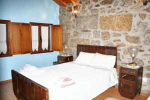 une chambre avec un lit et un mur en pierre dans l'établissement Spacious Family House in Nogueira with Garden, à Moita