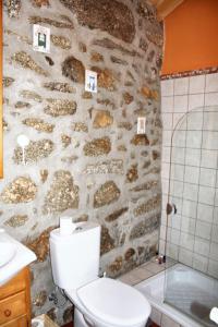 La salle de bains est pourvue de toilettes et d'un mur en pierre. dans l'établissement Spacious Family House in Nogueira with Garden, à Moita 17 autres photos