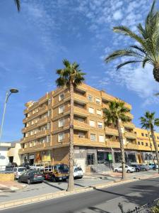 a building with palm trees in front of a street at APARTAMENTO TURISTICO 2ºD CARLOS III - Cerca de la playa in Roquetas de Mar