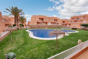 widok na dziedziniec z basenem z parasolami w obiekcie Seaside Apartment in Mojácar + Pool w mieście Mojácar