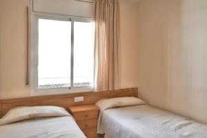 two beds in a room with a window at Comfortable apartment in Platja de la Pineda 70 m² with pool in La Pineda +16 photos