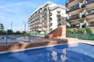 a swimming pool in front of a apartment building at Comfortable apartment in Platja de la Pineda 70 m² with pool in La Pineda