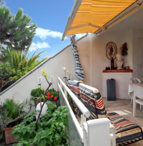 a patio with a couch and some plants and an umbrella at Maison familiale à Sainte-Marie in Sainte-Marie-Plage