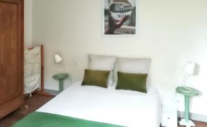 a bedroom with a white bed with two green pillows at Charmante maison avec cheminée à Saint-Jacut-de-la-Mer in Saint-Jacut-de-la-Mer