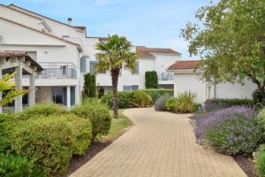 a walkway in front of a house with trees and bushes at Maison charmante à Vaux-sur-Mer avec piscine partagée in Vaux-sur-Mer