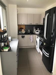 cocina con nevera negra, lavadora y secadora en Magellan, en Colombes 29 fotos más