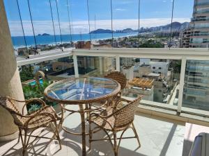 a glass table and chairs on a balcony with a view at A melhor vista da Enseada Guarujá! in Guarujá +33 photos