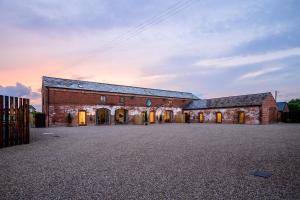 a large brick building with a sunset in the background at Bluebell Barn I Hot Tub I Games Room I Pets Welcome in Preesgreen