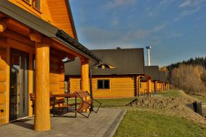 a wooden cabin with a table and chairs on a patio at Domki 15 szczytów in Zawoja