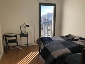 Un dormitorio con una cama y un escritorio y una ventana. en Magellan, en Colombes