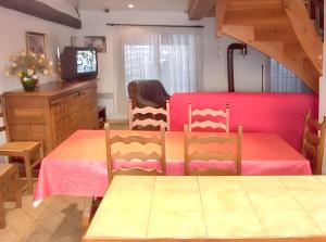 a dining room with a table and a pink bed at Maison chaleureuse près des pistes de Barcelonnette - Cheminée in Barcelonnette