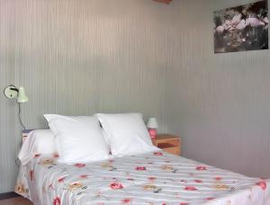 a bed with white sheets and red flowers on it at Maison chaleureuse près des pistes de Barcelonnette - Cheminée in Barcelonnette