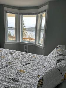 a bedroom with a bed with two windows with a view at Bay Bulls Waterfront Steps Totrail & Boat Tours! in Mobile