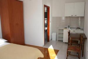 a bedroom with a bed and a table and a kitchen at Apartments Gordana in Trogir