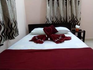 a bed with red and white pillows on it at Adb's Arudhra Homes in Tiruchirappalli