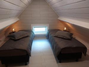 deux lits dans une chambre mansardée avec une fenêtre dans l'établissement Huis-Chalet aan Puyenbroeck, à Wachtebeke