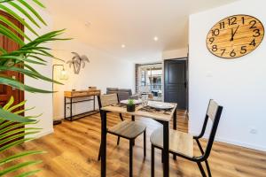 a dining room with a table and a clock on the wall at Chic des tropiques in Le Tampon