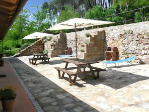 two picnic tables with umbrellas in front of a stone wall at Charming Apartment in Massa Marittima, Shared Pool in Massa Marittima +8 photos