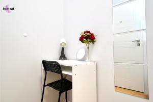 a white desk with a vase of flowers on it at MMRent Mystic Room in Gdańsk