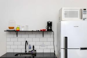 a kitchen with a sink and a white refrigerator at Studiohaus Pertence in São Paulo