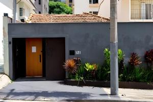 a gray building with a brown door and plants at Studiohaus Pertence in Sao Paulo