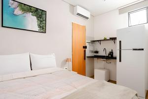 a white bedroom with a bed and a kitchen at Studiohaus Pertence in Sao Paulo