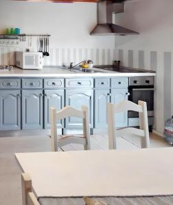 RequiãoにあるCharming House in Requião with Shared Poolの青いキャビネットとテーブルと椅子のあるキッチン