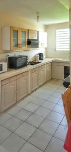 a kitchen with wooden cabinets and a tile floor at Maison confortable à Port-Louis + Proximité plages in Port-Louis +13 photos