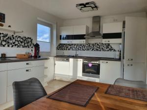 a kitchen with white cabinets and a wooden table with a dining room at Ferienwohnung Haunsheim in Haunsheim