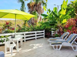 a patio with a table and chairs and an umbrella at Studio agréable avec vue sur la mer à Marigot - 30 m² + Jardin. in Marigot