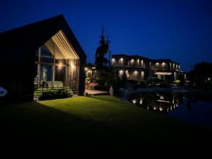 a house lit up at night next to a body of water at Black House- Lake garden sauna in Tīnūži