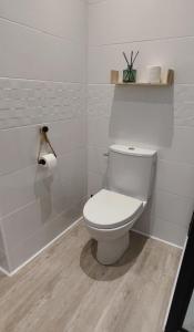 a white bathroom with a toilet and a roll of toilet paper at Charming studio in downtown in Montélimar
