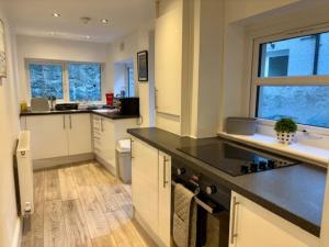 Una cocina con gabinetes blancos y una encimera negra. en Charming 2BR House in the Heart of Colwyn Bay, en Colwyn Bay