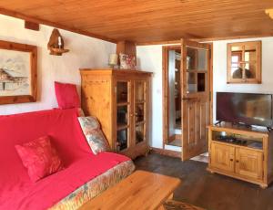 a living room with a red couch and a flat screen tv at Appartement charmant à Arvieux, 50 m², vue montagne in Arvieux